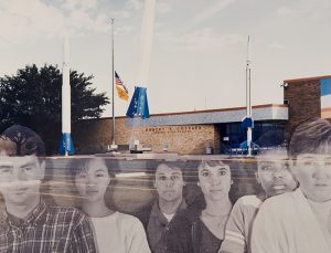 A collaged photograph depicting a one-story, brown building with tall blue-and-white structures resembling rockets in the background and a parking lot in the foreground. Six translucent black-and-white portraits of men and women of varying ethnicities and genders are overlaid across the parking lot.