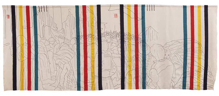 A 15-foot-wide rectangular fabric that has the recognizable sets of Hudson's Bay Blanket stripes (indigo, yellow, red and green) -- one set on each end with two sets equidistant to the center. An outlined scene, stitched in black thread, shows a large group of people, most having their backs to us, except for the face of a child who is a person's arms. People in the distance show raised fists.